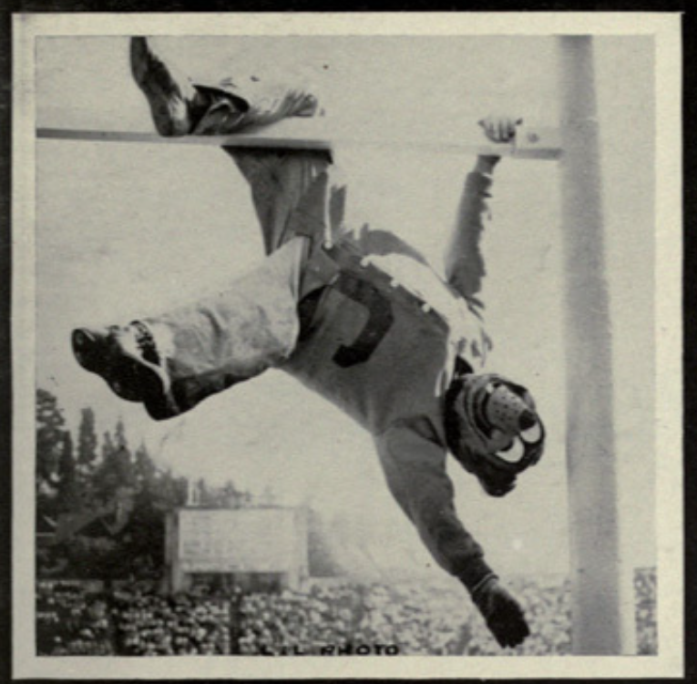 Archival scan: Oski hanging upside down from a goalpost. Photo credit: Photographer/artist uncredited in supplied scan.