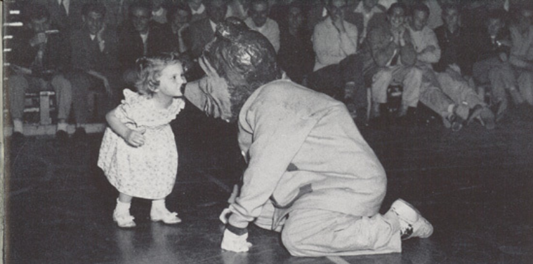 Archival scan: Oski kneeling to greet a small child. Photo credit: Photographer/artist uncredited in supplied scan.
