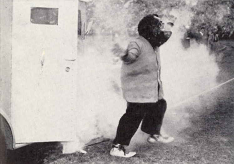 Archival scan: Oski beside a vehicle with smoke behind him. Photo credit: Photographer/artist uncredited in supplied scan.