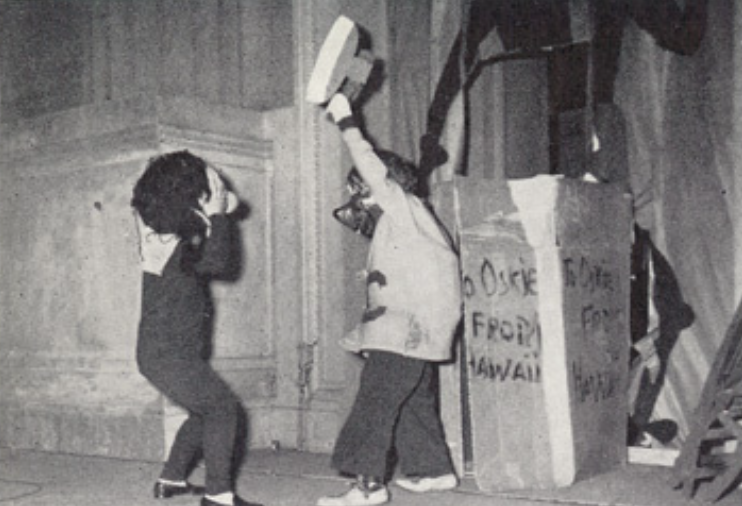 Archival scan: Oski emerging beside a large shipping crate. Photo credit: Photographer/artist uncredited in supplied scan.