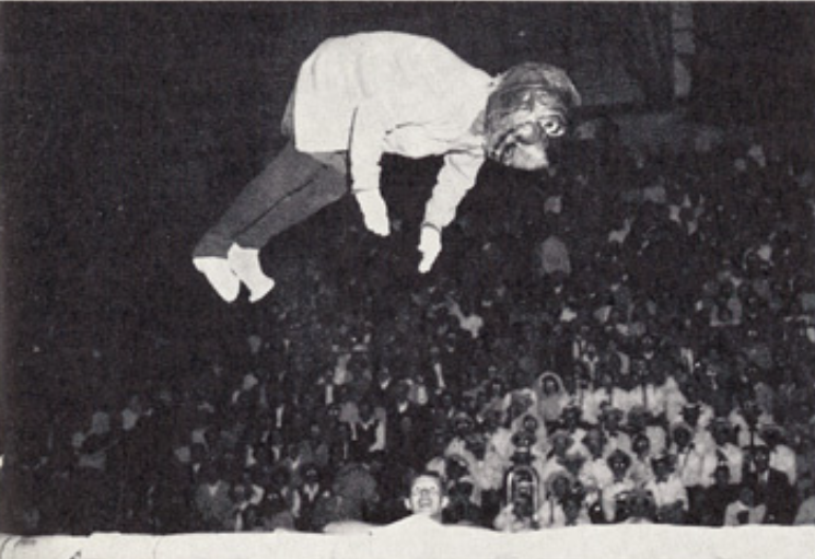 Archival scan: Oski tumbling through the air over a stadium crowd. Photo credit: Photographer/artist uncredited in supplied scan.
