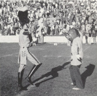 Archival scan: Oski facing a drum major on the field. Photo credit: Photographer/artist uncredited in supplied scan.
