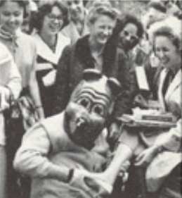 Archival scan: Oski reclining with his feet raised among a crowd. Photo credit: Photographer/artist uncredited in supplied scan.
