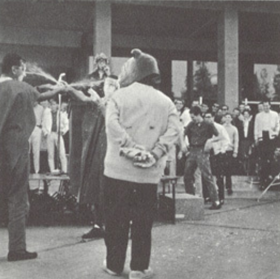 Archival scan: Oski standing with hands behind his back near officials. Photo credit: Photographer/artist uncredited in supplied scan.