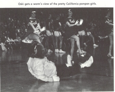 Archival scan: Oski lying on the floor in front of a seated group. Photo credit: Photographer/artist uncredited in supplied scan.