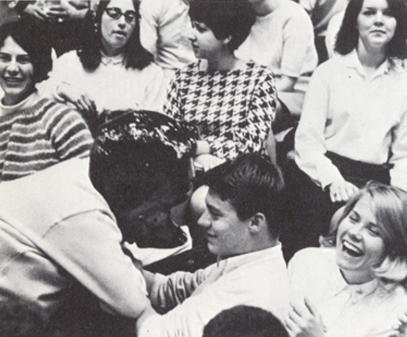 Archival scan: Oski leaning back among laughing spectators. Photo credit: Photographer/artist uncredited in supplied scan.