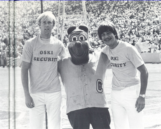 Archival scan: Oski between two people wearing Oski Security shirts. Photo credit: Photographer/artist uncredited in supplied scan.