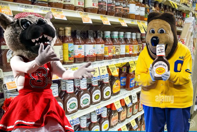 Edited image of Oski and Mrs. Wuf in a grocery sauce aisle. Existing Alamy watermarks are visible. Photo credit: Original editor unverified; image supplied by @calwokebot; Alamy watermarks visible.